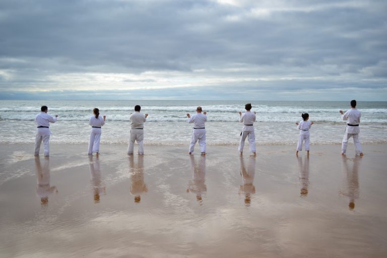 Beautiful shot of karate players practicing at the seashore