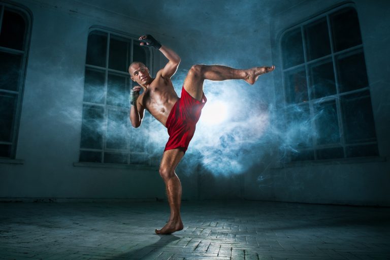The young man kickboxing in blue smoke
